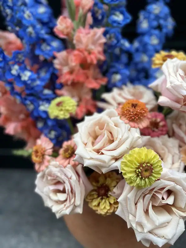 Statement wedding arrangement with blue delphinium, roses and zinnias