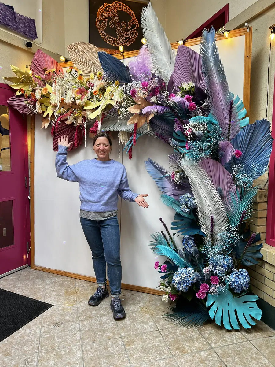 Doorway floral installation of painted palms, hydrangea and feathers